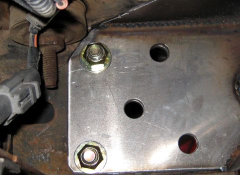 1996 Ford Bronco - A metal bracket with multiple bolt holes is attached to the vehicle's frame, with electrical wiring visible.