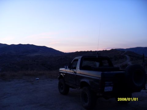 1990 Ford Bronco - 1990 Ford Bronco parked on a dirt road with mountains in the background during dusk.