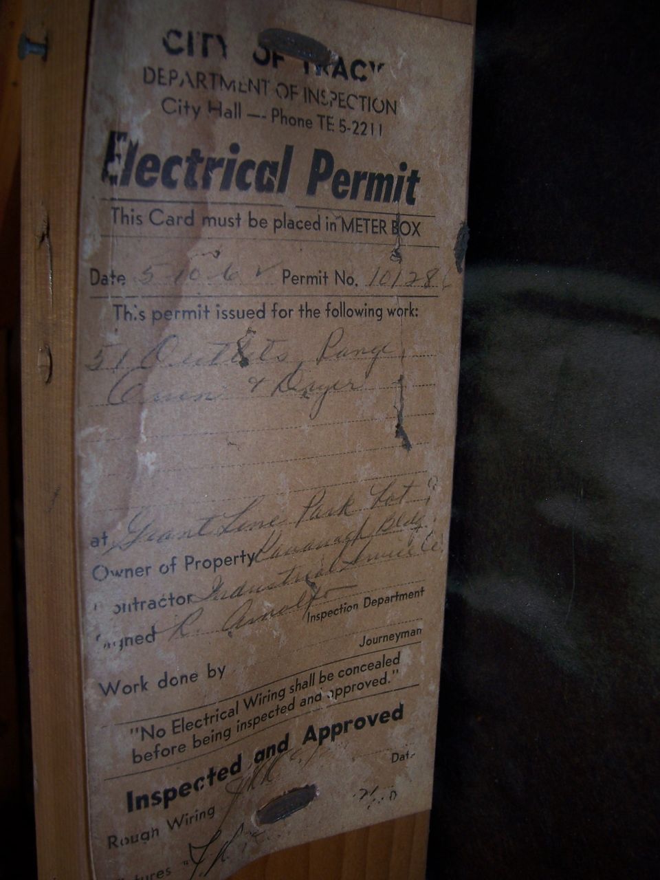 Aged City of Tracy electrical permit card stapled to a wood stud