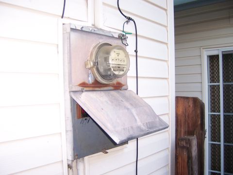 1991 Ford Bronco - An outdoor electrical meter box with a partially opened metal cover is attached to the side of a house.