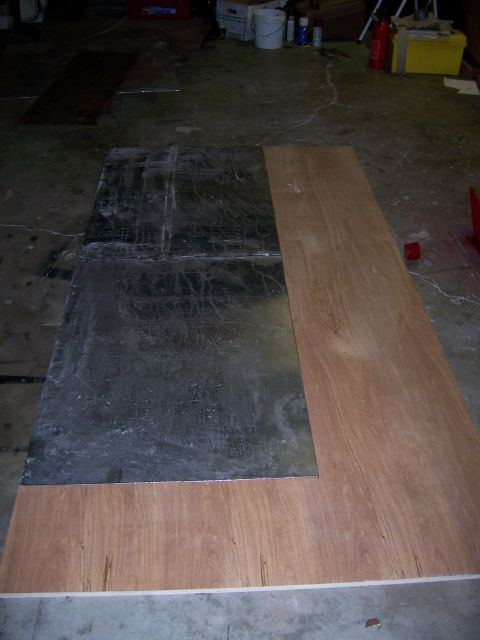 1991 Ford Bronco - Two sheets of material, one metal and one wood, are laid out on a concrete floor.