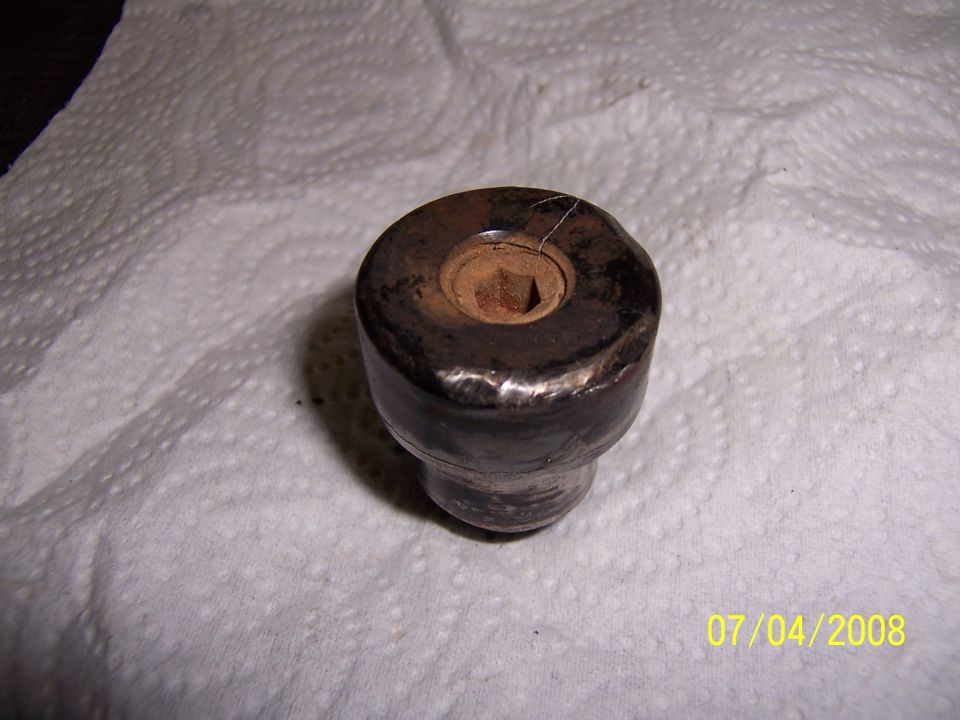 Metal part with hexagonal recess on paper towels, showing rust and wear