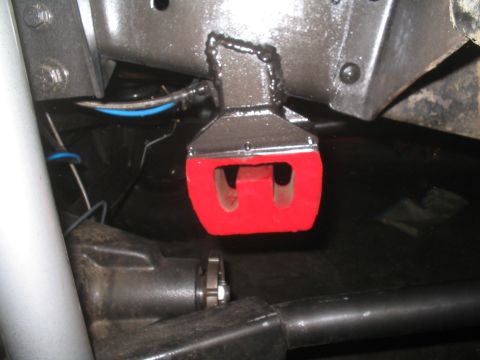 1979 Ford Bronco - Underside view of a vehicle's suspension system, highlighting a red bushing and metal components.