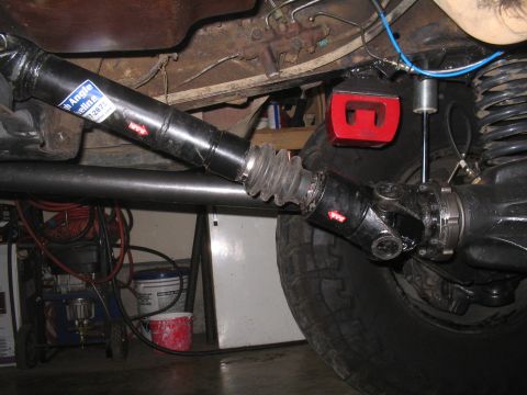 1979 Ford Bronco - Close-up view of the driveshaft and suspension components, including a "High Angle Driveline" sticker and a red shock absorber mount.
