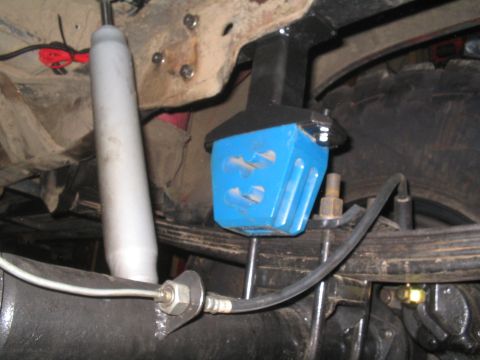 1979 Ford Bronco - Undercarriage view of a vehicle's suspension system, focusing on a blue block and shock absorber.