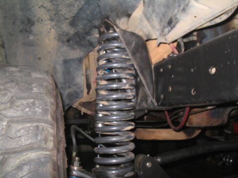 1979 Ford Bronco - Close-up view of the suspension system, including a large coil spring and tire, with visible frame elements.