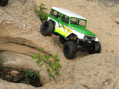1996 Ford Bronco - An RC rock crawler navigates a rocky terrain with green and white body graphics.