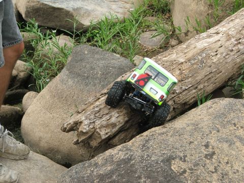1996 Ford Bronco - A remote-controlled vehicle navigates a challenging obstacle course of rocks and a fallen tree.