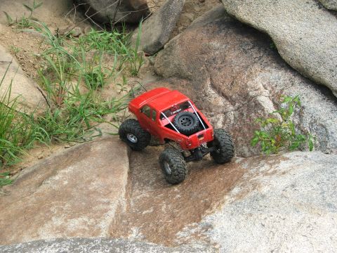 1996 Ford Bronco - A red remote control rock crawler navigates a challenging rocky landscape.