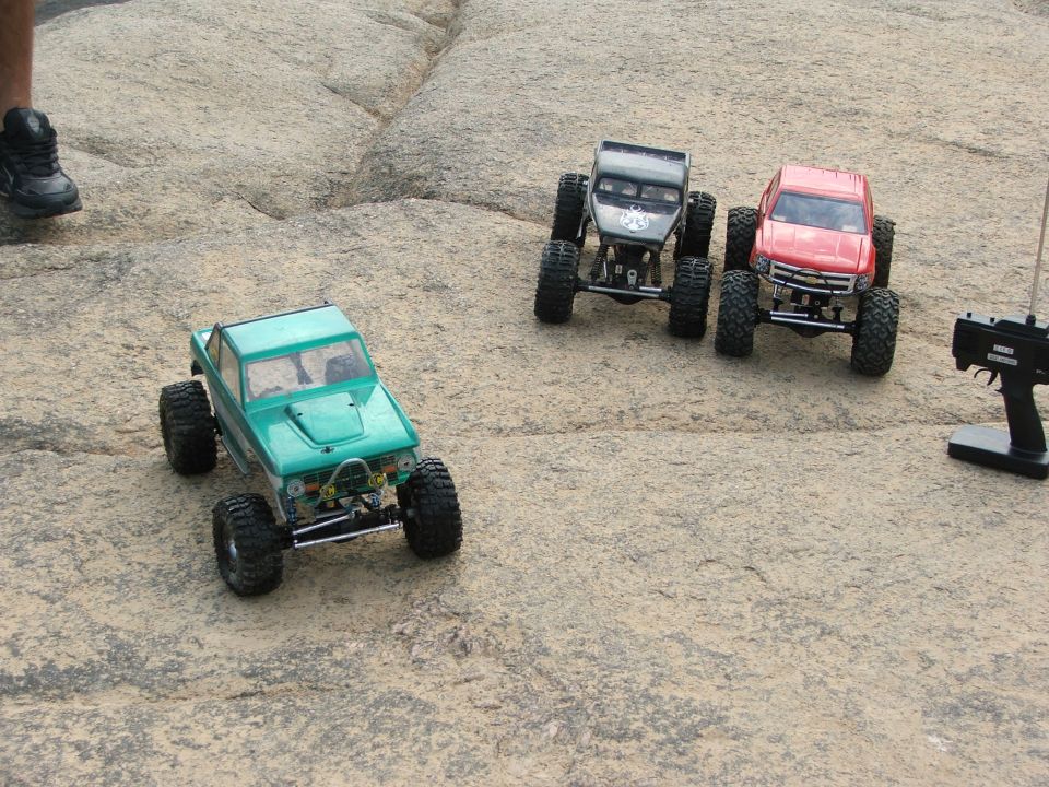 Three remote control rock crawling trucks on rocky terrain
