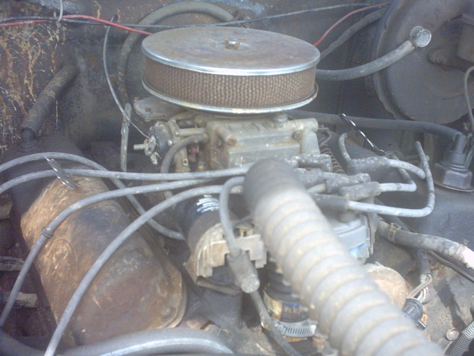 1978 Ford F-150 engine bay with a carburetor and air filter. Rusty metal and wires are visible