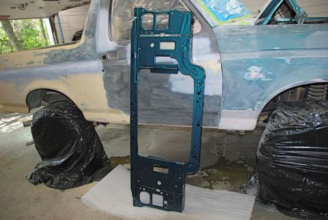 1996 Ford Bronco - Teal metal core support part is positioned in front of a 1996 Ford Bronco that is in the process of body repair.
