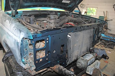1996 Ford Bronco - The front end of a teal Ford Bronco is disassembled, revealing the engine and radiator in a workshop setting.