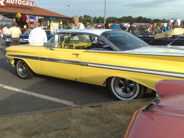 Yellow and white classic car with chrome trim parked at an outdoor event