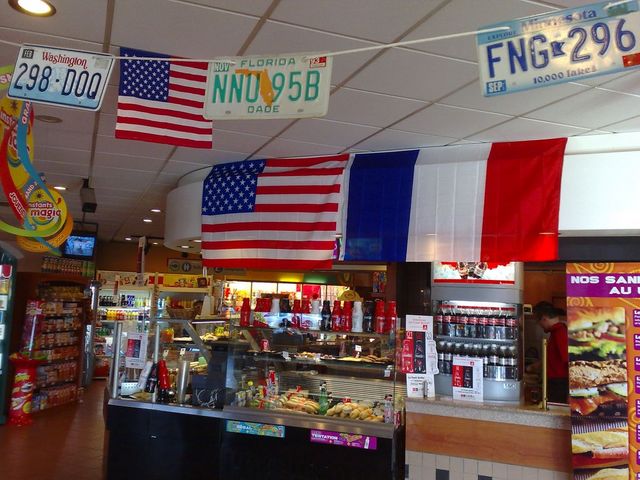 Interior of a store decorated with American and French flags, and license plates