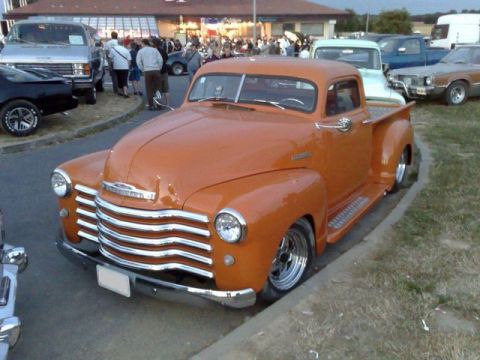 1991 Ford Crown Victoria - This orange Chevrolet pickup truck has a distinctive chrome grille and custom wheels.