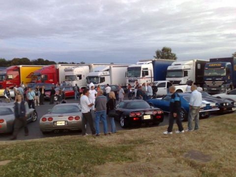 1991 Ford Crown Victoria - A gathering of vehicles and people under a cloudy sky.