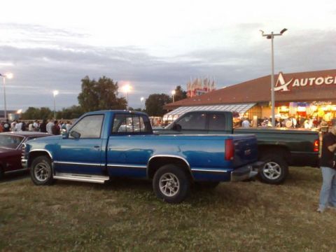 1991 Ford Crown Victoria - Two pickup trucks are parked side-by-side at an outdoor gathering.