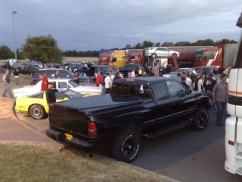 1991 Ford Crown Victoria - A black pickup truck is parked at an outdoor car meet with many other vehicles present.