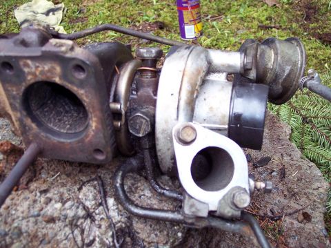 1995 Ford Probe - Used turbocharger removed from a vehicle, resting on the ground.