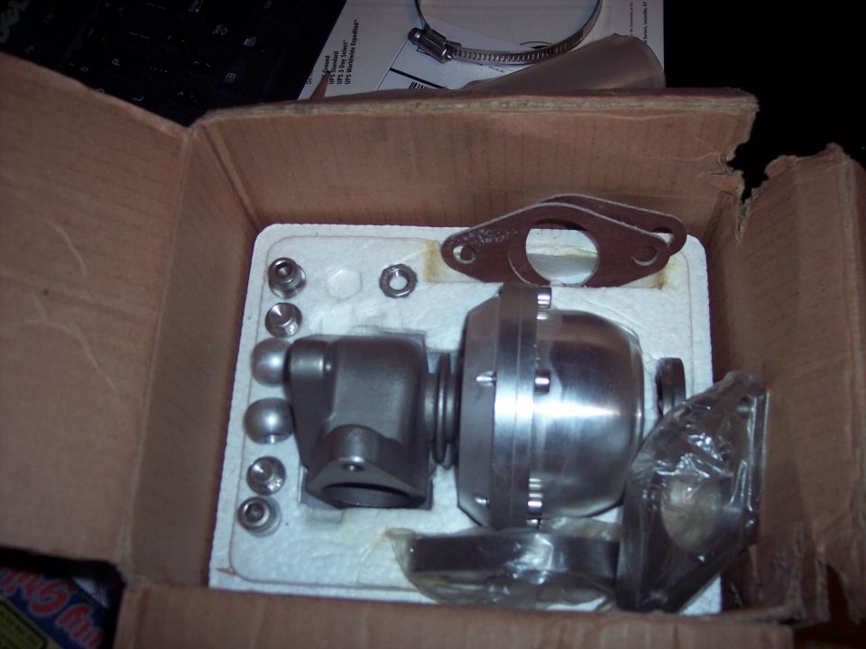 New turbocharger wastegate and gaskets in a box, with a hose clamp and some paperwork on top