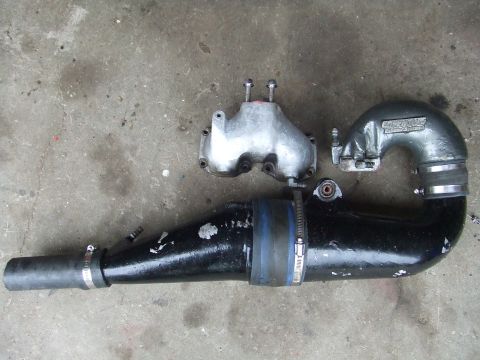 1998 Kawasaki JH1100-A4 1100 ZXi - Close-up of a jet ski's intake manifold and exhaust pipe assembly lying on a concrete surface.