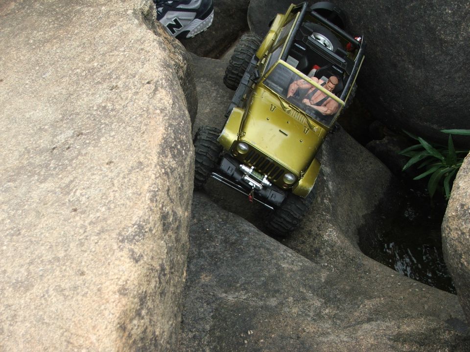 Yellow RC rock crawler Jeep navigating a rocky terrain