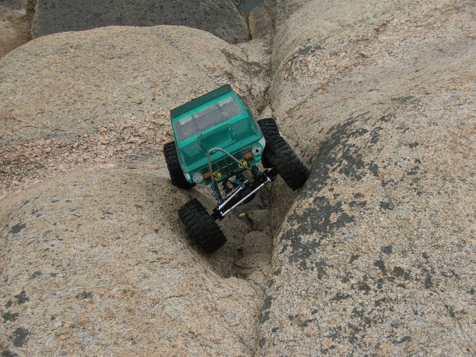 Green remote control rock crawler navigating a rocky crevice