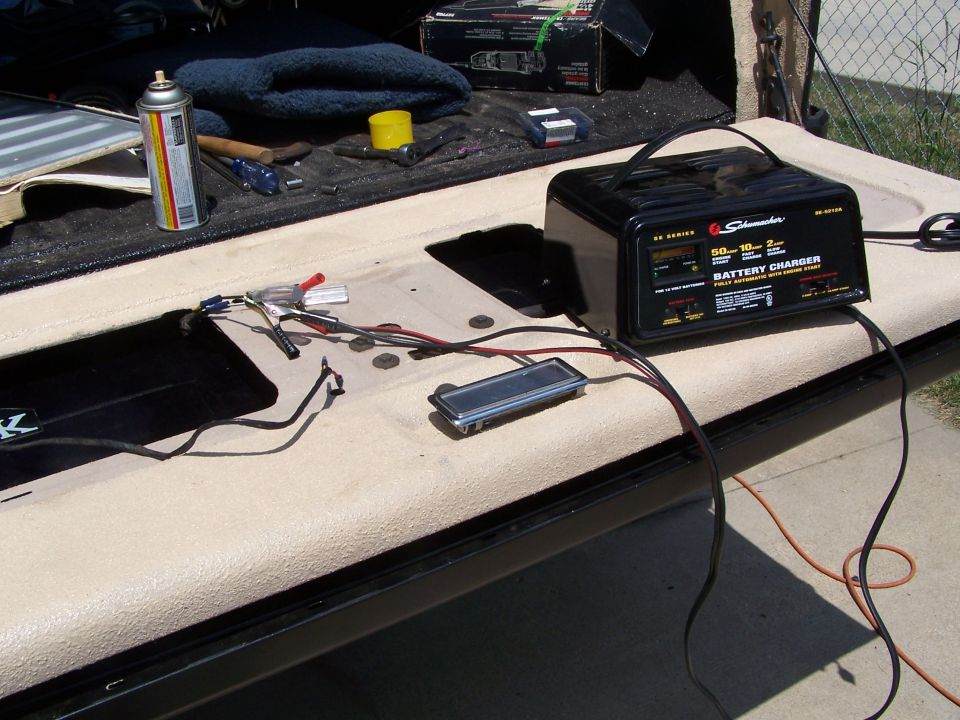 Tailgate open with a Schumacher battery charger, spray can, and tools laid out