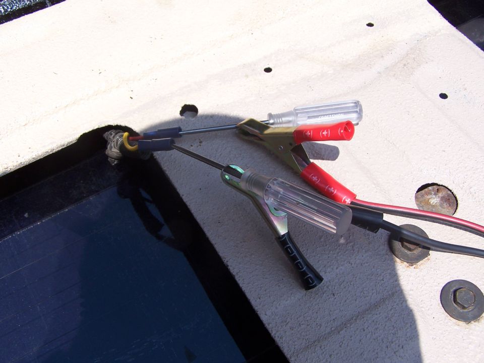 Automotive test light and jumper clips attached to a wire near a dark surface