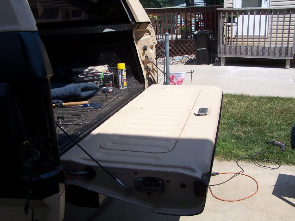 Tailgate of a pickup truck open, showing tools and supplies in the bed