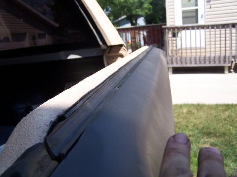 1986 Ford Bronco - Close-up of a vehicle's tailgate edge, with a finger visible on the right side.