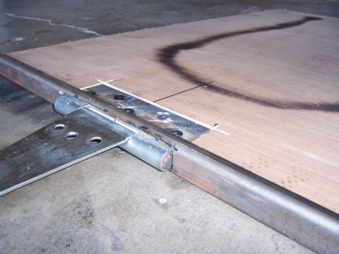 1991 Ford Bronco - Metal tubing and bracket assembly on a plywood surface, possibly for a fabrication project.