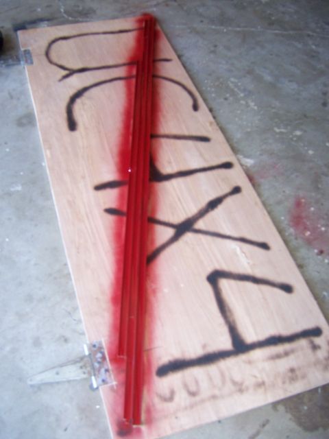 1991 Ford Bronco - A wooden door with red metal trim and black spray paint markings is shown, possibly part of a welding project.