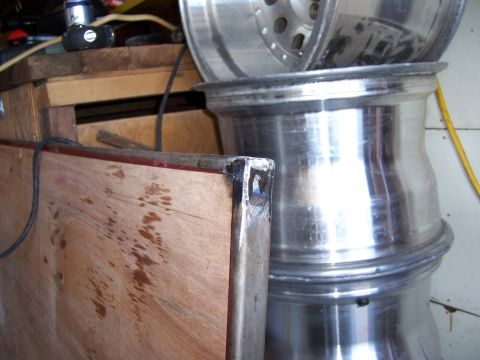 1991 Ford Bronco - Several large aluminum wheels are stacked together in what appears to be a workshop or garage setting.