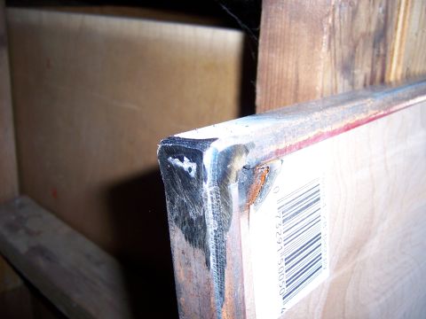 1991 Ford Bronco - A close-up view of a welded metal corner, showing a barcode label attached to a wooden surface.