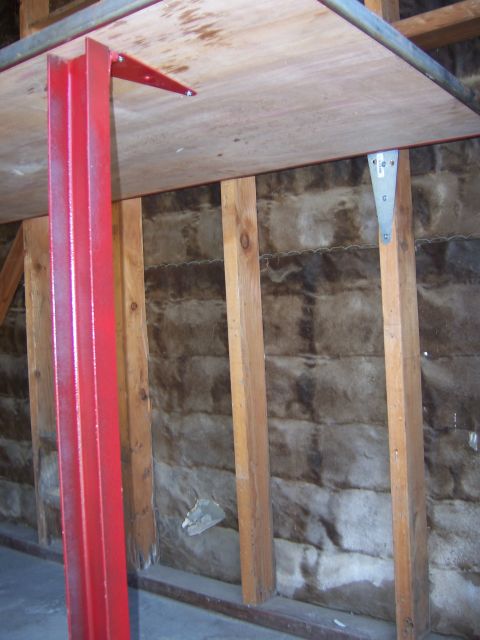 1991 Ford Bronco - Red metal support for a wooden table, attached to a wall with wooden studs.