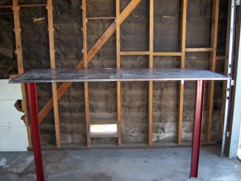 1991 Ford Bronco - A metal workbench stands in a garage with exposed insulation and wooden studs.