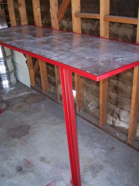 1991 Ford Bronco - A welding table with a red frame and a speckled top is positioned in a workshop environment.
