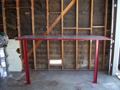 1991 Ford Bronco - A metal table stands in a garage with unfinished walls and stacked items to the left.