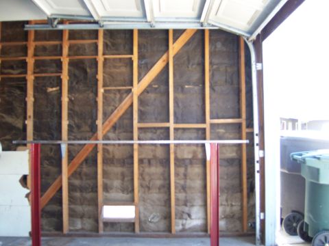 1991 Ford Bronco - The interior of a garage shows unfinished walls with insulation and wooden framing, along with a metal bar supported by red posts.
