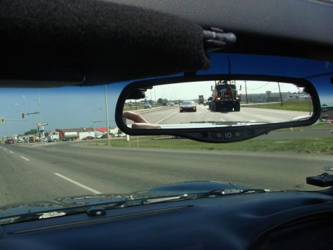 2001 Chevrolet Corvette - A red sports car is seen in the rearview mirror, following a large semi-truck on a highway.
