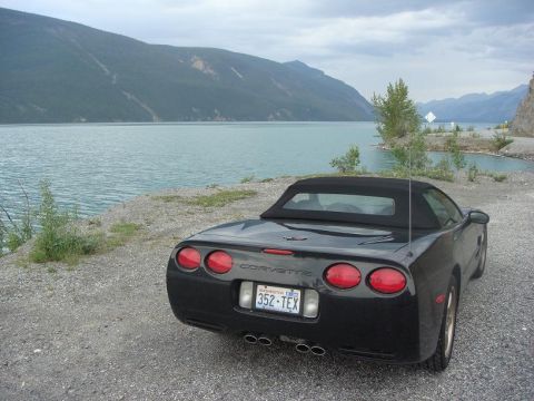2001 Chevrolet Corvette - A black 2001 Chevrolet Corvette convertible is parked by a lake with mountains in the background.