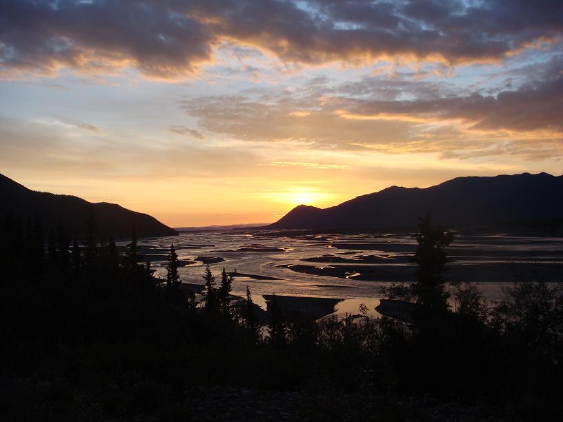 River delta with sandbars and mountains under a colorful sunset sky