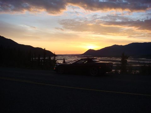 2001 Chevrolet Corvette - A convertible Corvette is parked by the road as the sun sets behind mountains and a river.