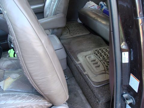 1992 Ford Bronco - The rear interior of a 1992 Ford Bronco shows worn leather seats and a storage area with floor mats.