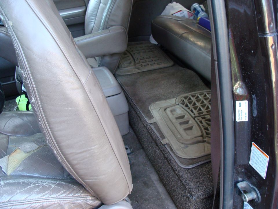 1992 Ford Bronco interior rear storage area with worn leather seats and floor mats