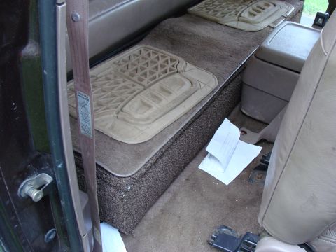 1992 Ford Bronco - Rear storage area of a vehicle, showing floor mats and some scattered documents.