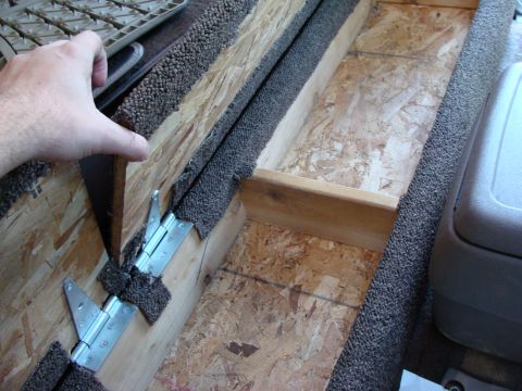 1992 Ford Bronco - A custom-built wooden storage compartment is shown inside a vehicle, carpet trim and metal hinges.