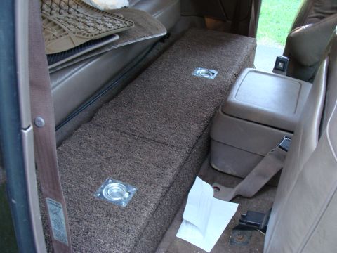 1992 Ford Bronco - Interior view of the rear seat storage area in a 1992 Ford Bronco, showing carpeted bins and a center console.